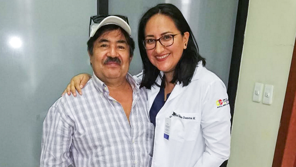 Egy férfi és egy nő mosolyogva állnak egymás mellett. A nő a karját a férfi köré fonja