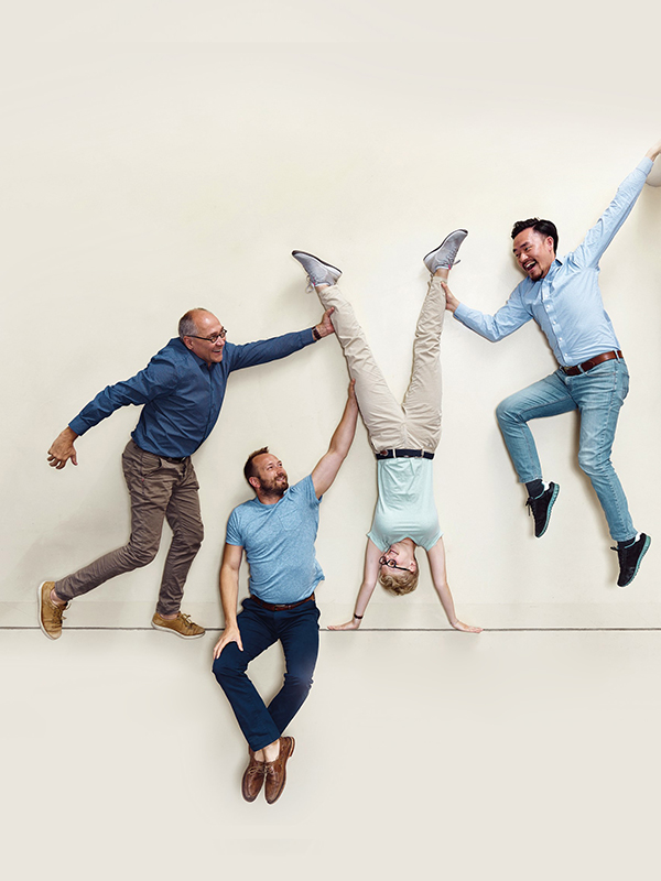 Egy személy fejjel lefelé fordítva, és három másik személy tartja őket